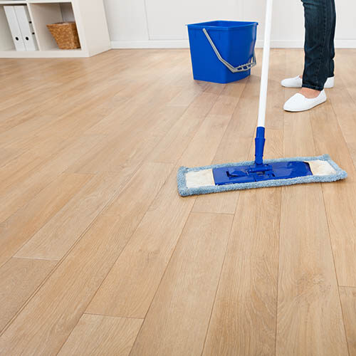 Low section of young woman mopping hardwood floor at home