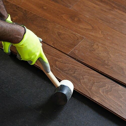 Worker installing hardwood with tool | Color Interiors